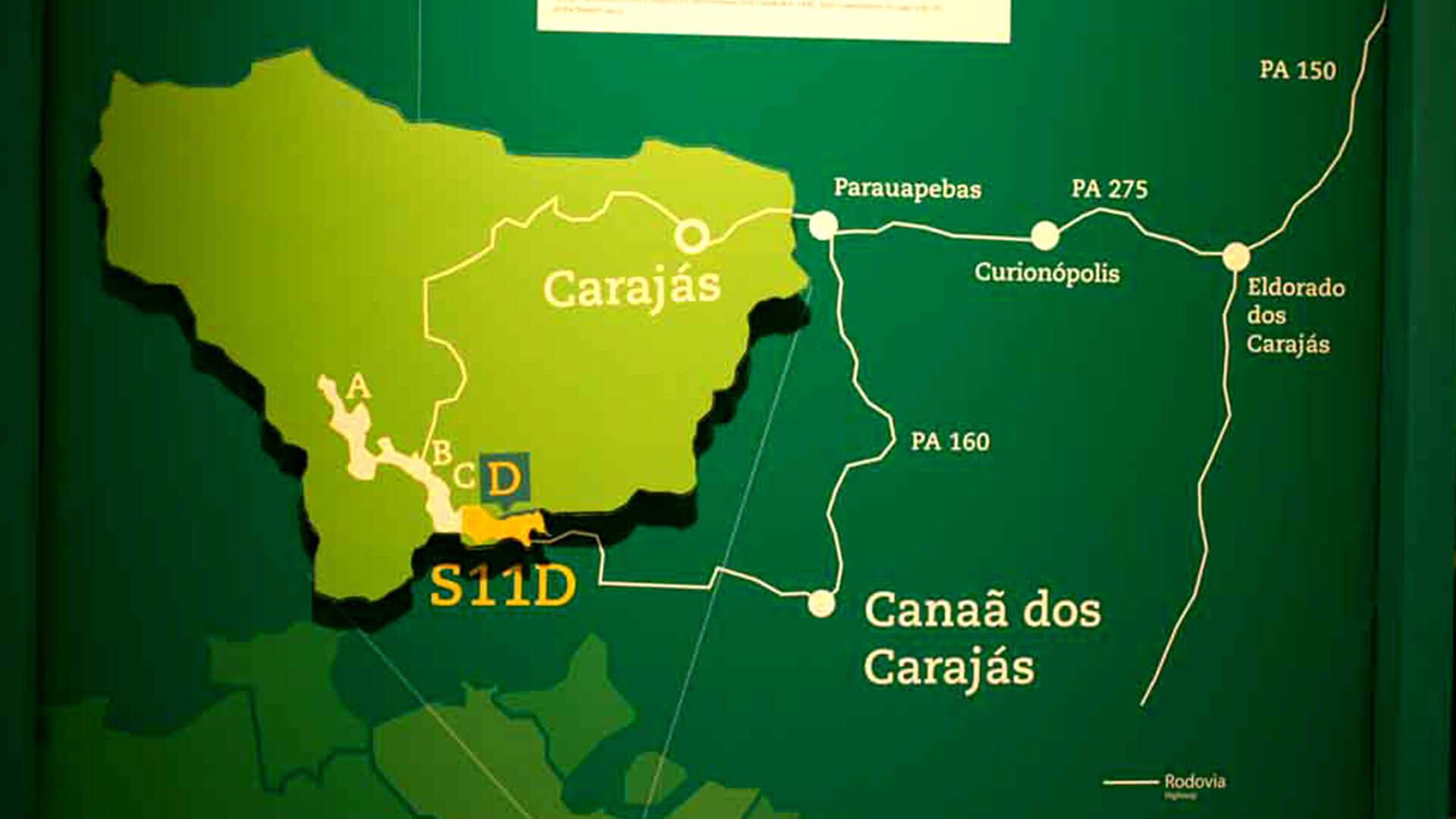 Mapa detalhado em tons de verde mostrando a localização do projeto de mineração S11D na região de Carajás, Pará, Brasil. O mapa exibe cidades próximas (como Parauapebas, Curionópolis, Canaã dos Carajás e Eldorado dos Carajás) e as rodovias de acesso (PA 150, PA 275 e PA 160).