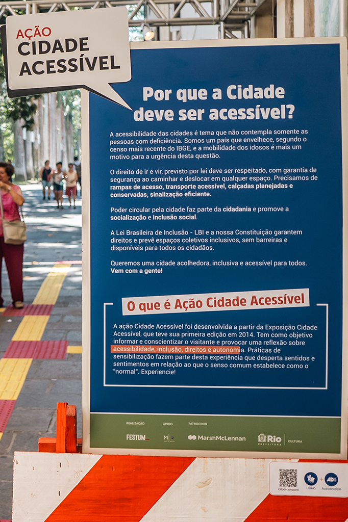 Placa de texto com fundo azul e conteúdo em branco, explica os motivos pelo qual a Cidade deve ser acessível, explica os direitos dos cidadão através da Lei Brasileira de inclusão e sobre a Contituição que prevê espaços coletivos inclusivos, sem barreiras e disponíveis para todos.