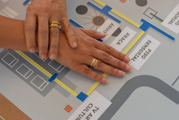 Mapa t&aacute;til da exposi&ccedil;&atilde;o Cidade Acess&iacute;vel. Duas m&atilde;os est&atilde;o interagindo com o mapa.